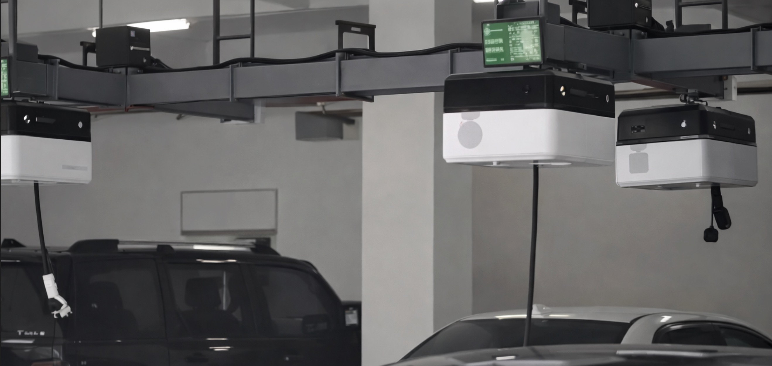 Vue d'ensemble d'un parking moderne en Chine où plusieurs voitures électriques sont rechargées par des robots de plafond, avec des câbles descendant vers les véhicules.
