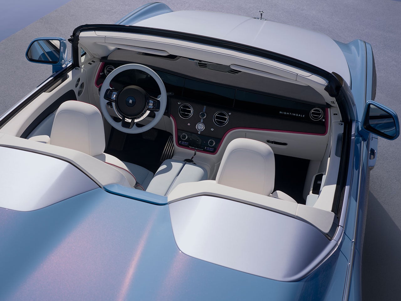 Intérieur luxueux du Rolls-Royce Project Nightingale, avec des sièges en cuir clair, un tableau de bord en bois poli et des accents métalliques, mettant en valeur le volant et les commandes.