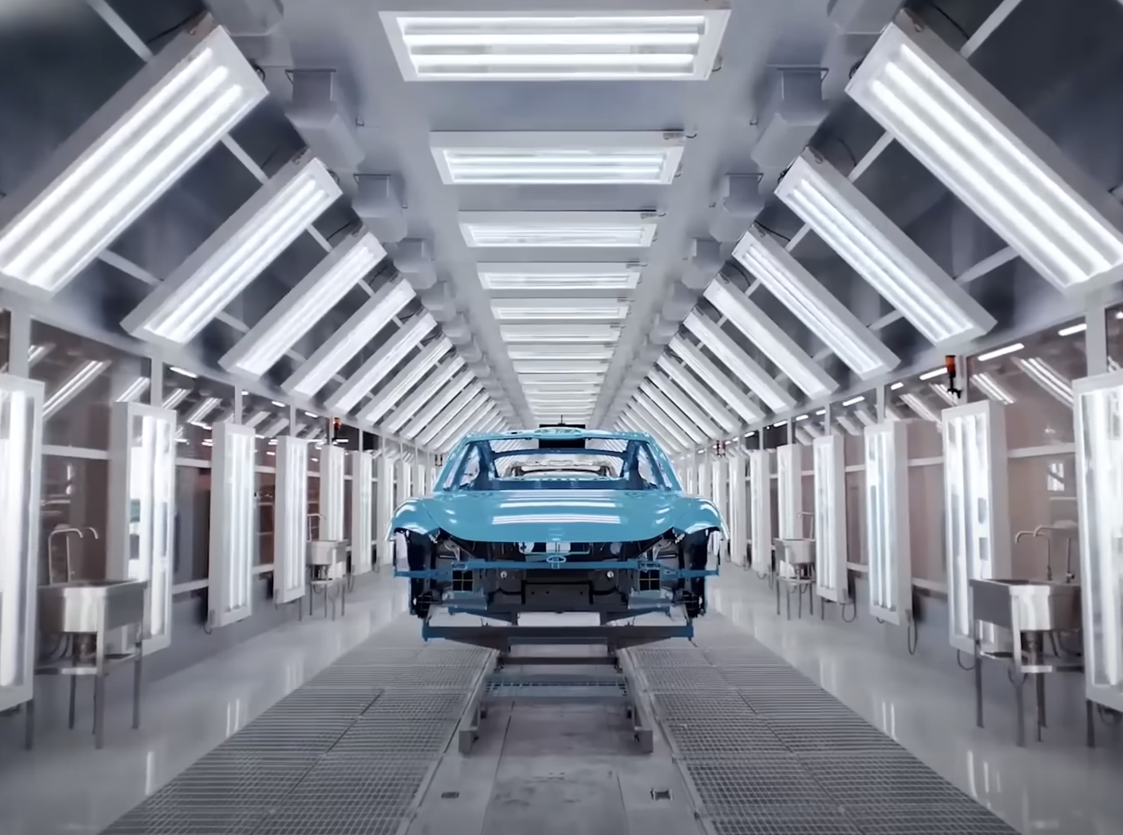 Vue d'une usine de fabrication de voitures électriques Xiaomi SU7, montrant des robots en action sur la chaîne d'assemblage.