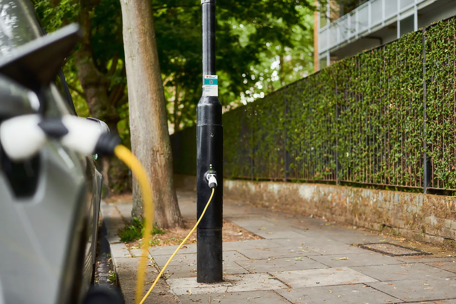 Image d'une borne de recharge Ubitricity intégrée à un lampadaire à Londres, avec une voiture électrique en charge.