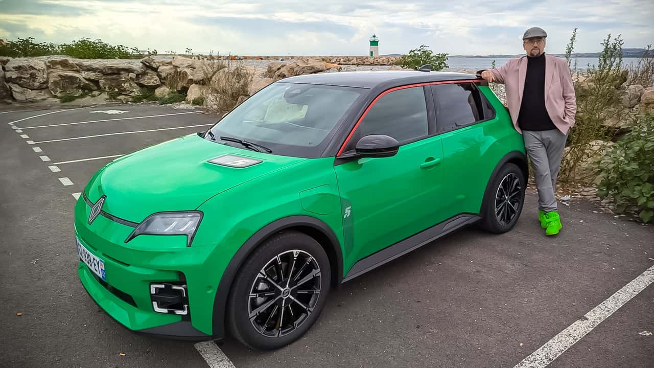 Une Renault R5 E-Tech électrique jaune vif, garée dans une rue pavée d'une ville européenne, avec des passants en arrière-plan.