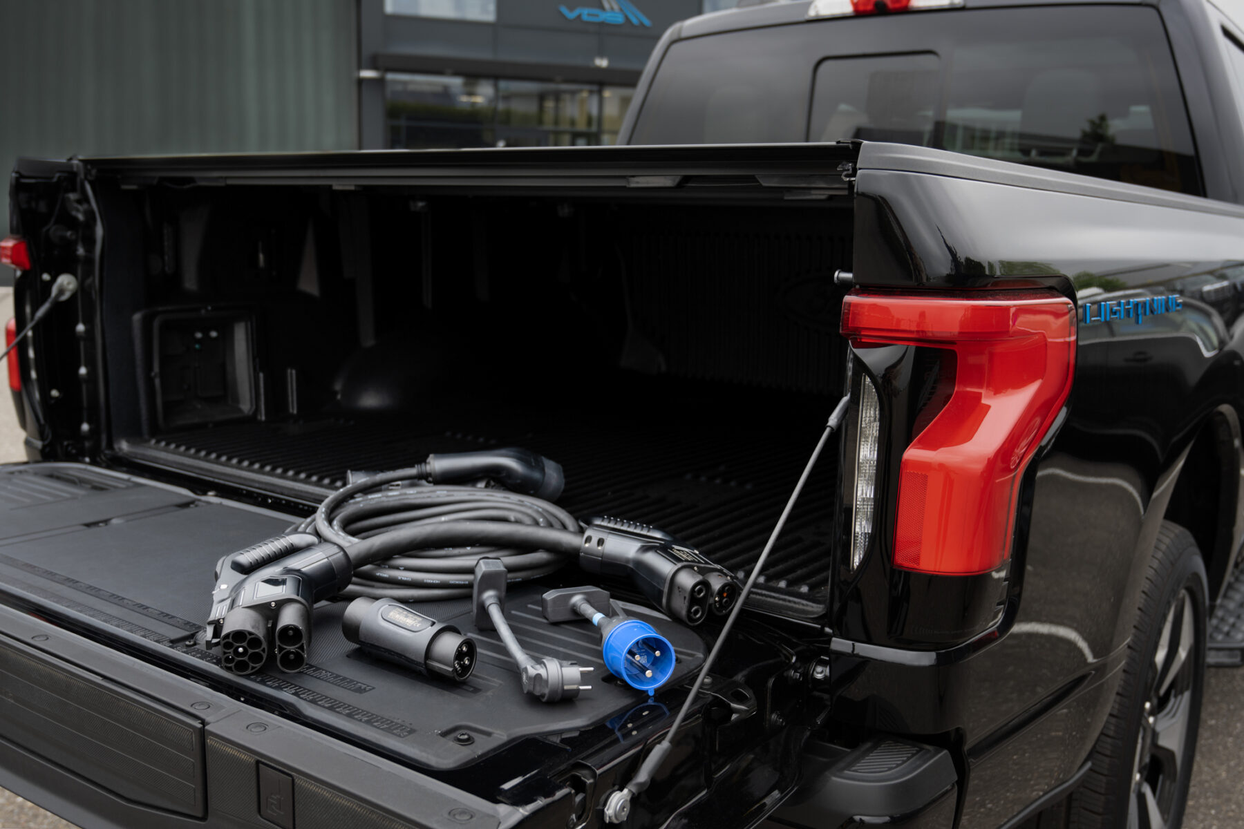 Un Ford F-150 Lightning gris branché à une borne de recharge rapide dans un environnement urbain européen.