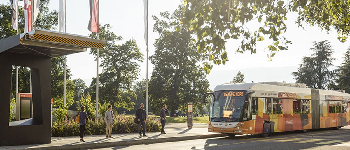 Un bus électrique moderne se recharge à une station Hitachi Energy Grid-eMotion Flash. La station est discrète et le bus est en train de charger ses batteries rapidement.