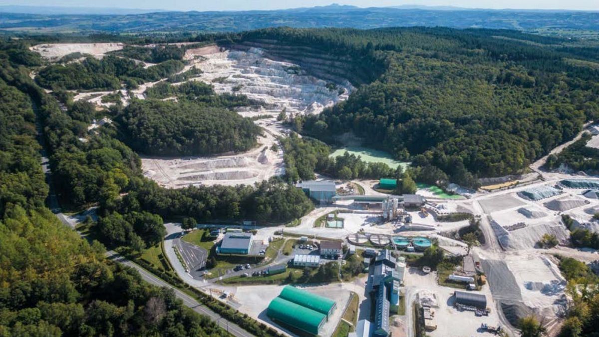 Photographie aérienne d'une mine de lithium à ciel ouvert, avec des engins de chantier et des bassins de traitement, située dans la région de l'Allier en France.