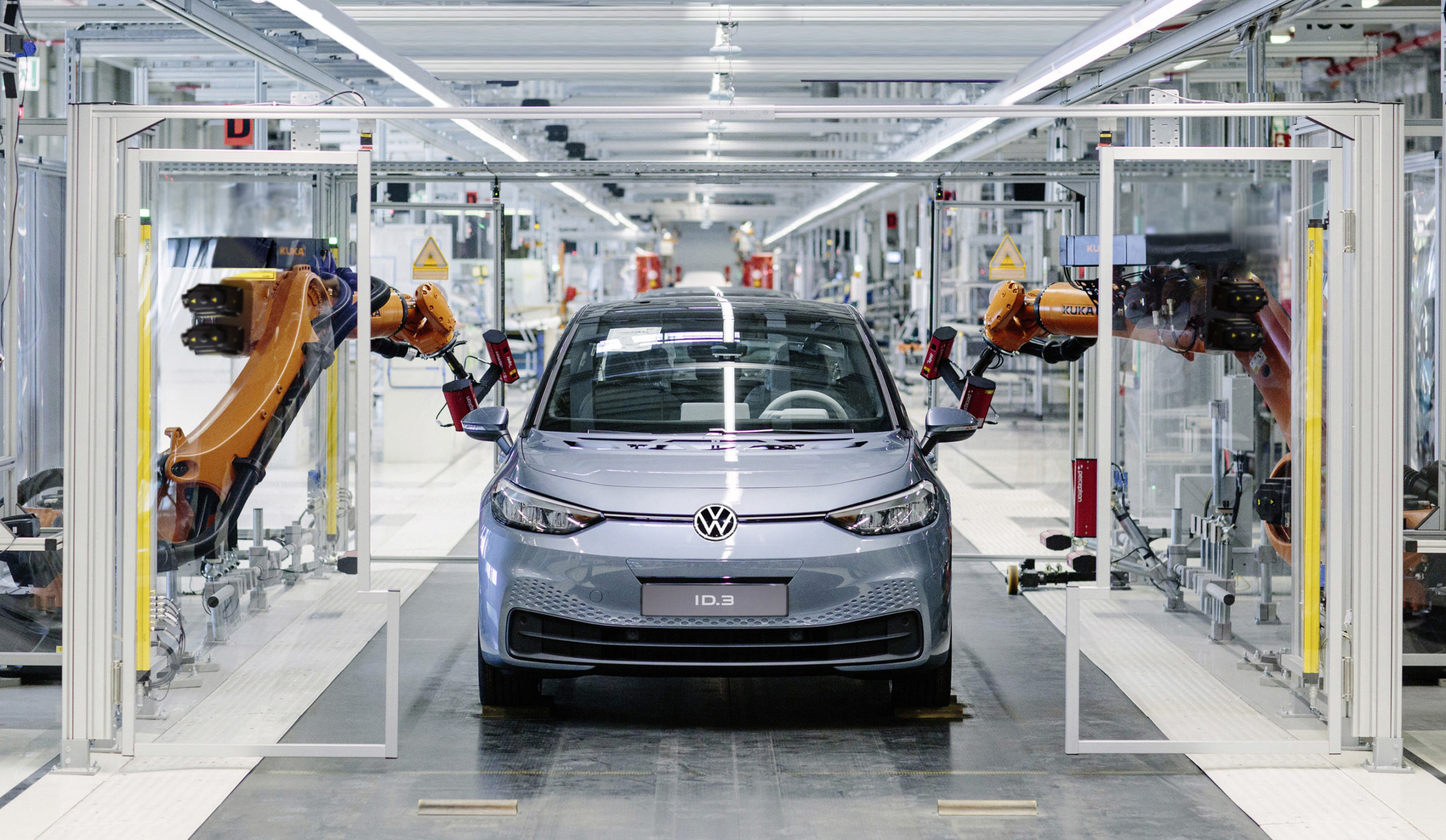 Vue d'une chaîne de montage de voitures électriques dans une usine européenne, avec des robots et des employés.