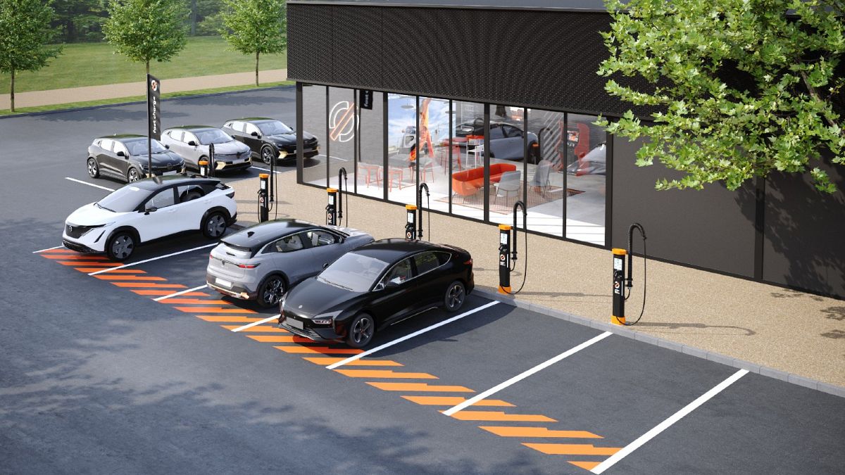 Une voiture électrique Renault en charge rapide dans une station moderne en ville, avec des bâtiments européens en arrière-plan.