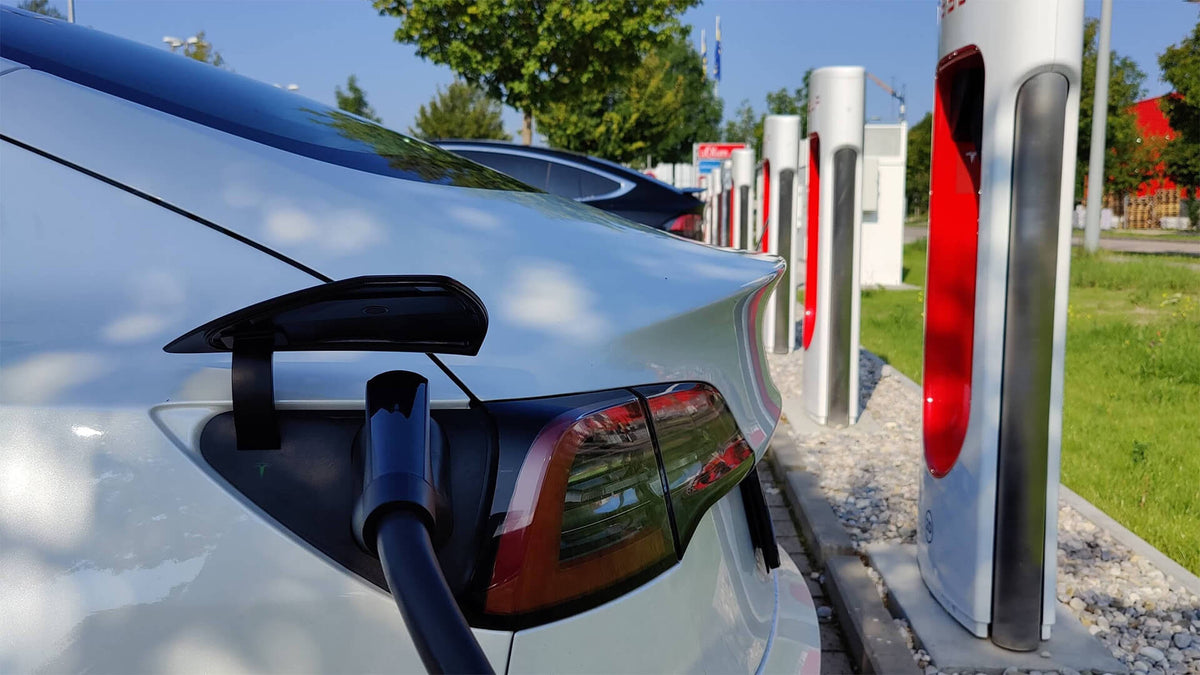 Deux voitures Tesla, un Model 3 et un Model Y, en train de recharger leurs batteries à une station Supercharger.