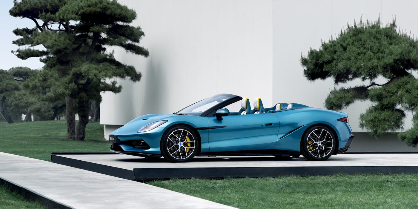 Une Denza Z cabriolet électrique bleue, garée dans une rue de ville au coucher du soleil, mettant en valeur son design futuriste.