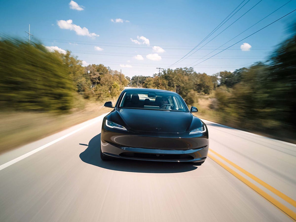 Une Tesla Model 3 Grande Autonomie de 2026 roule sur une autoroute, symbolisant l'efficacité des véhicules électriques pour les longues distances.