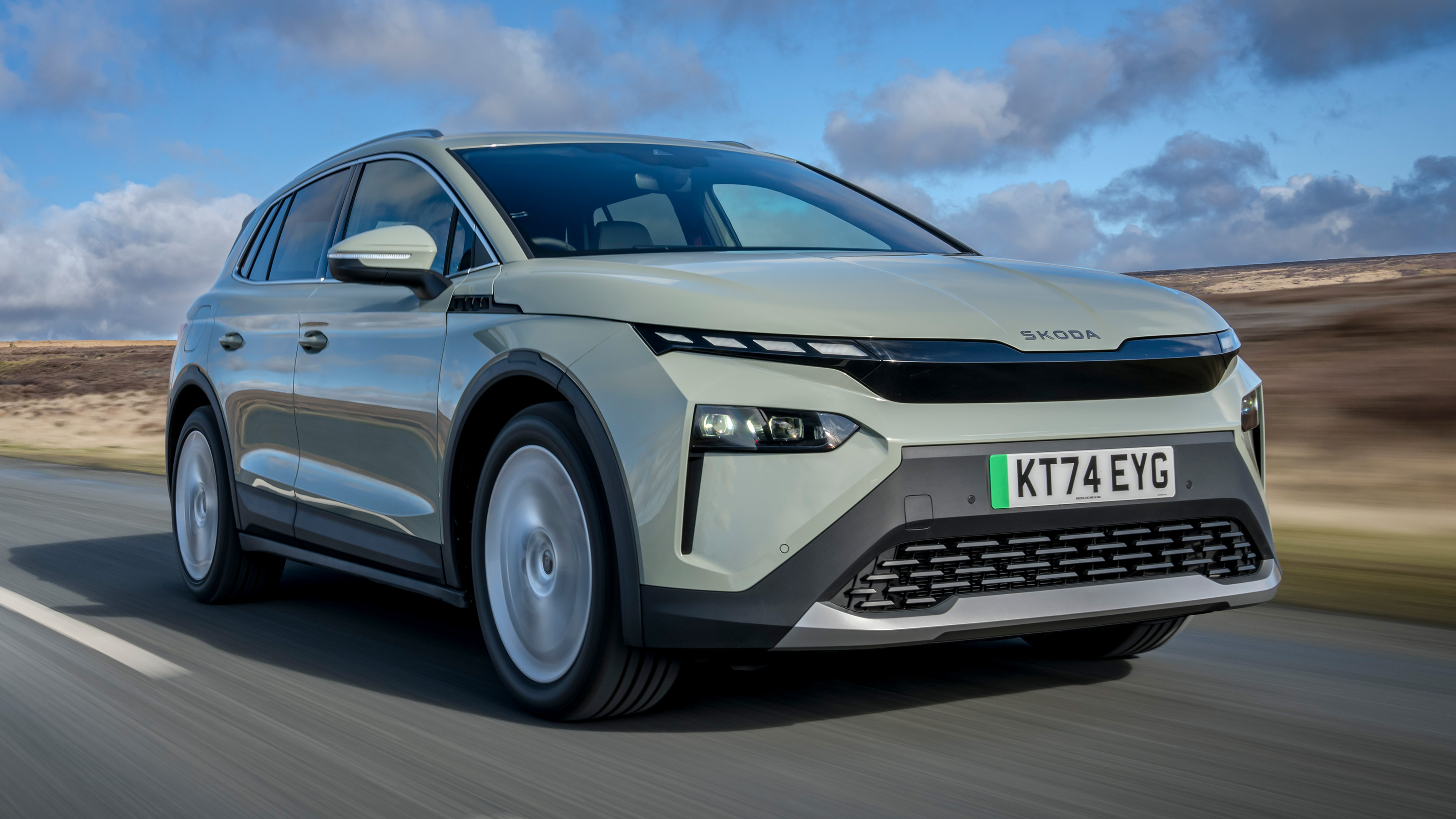 Un Skoda Elroq électrique 2026 roulant sur une route sinueuse à travers un paysage verdoyant.