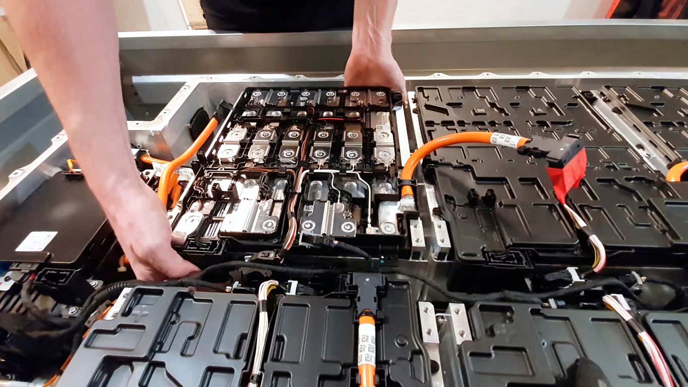 Un mécanicien inspectant de près la batterie d'un véhicule électrique avec des outils de diagnostic.