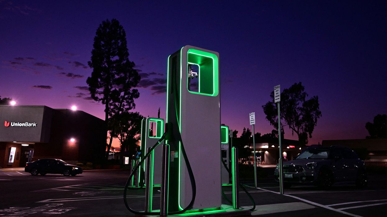 Image d'une station de recharge rapide pour véhicules électriques sur une autoroute la nuit.