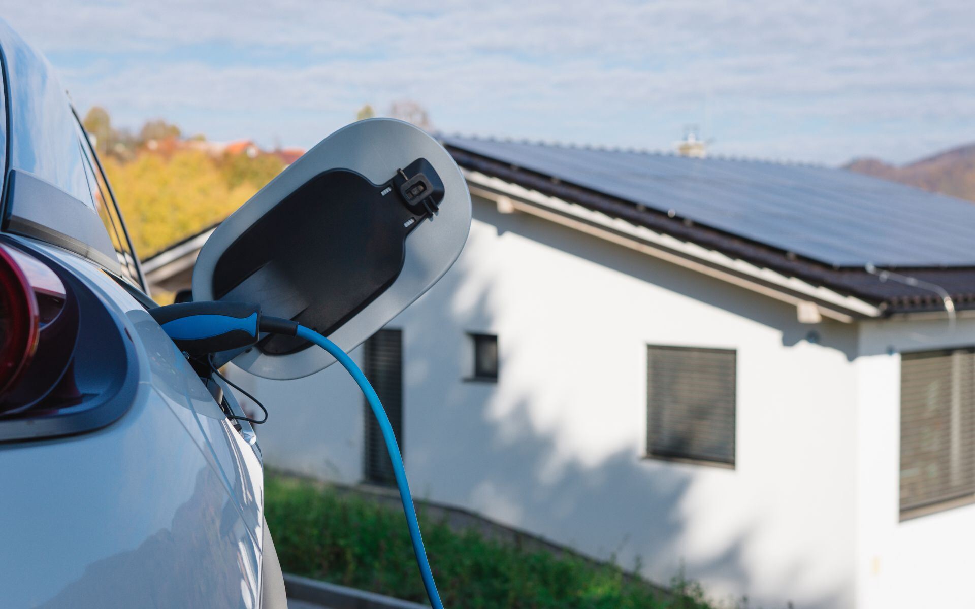 Image d'une voiture électrique en charge à la maison avec des panneaux solaires.