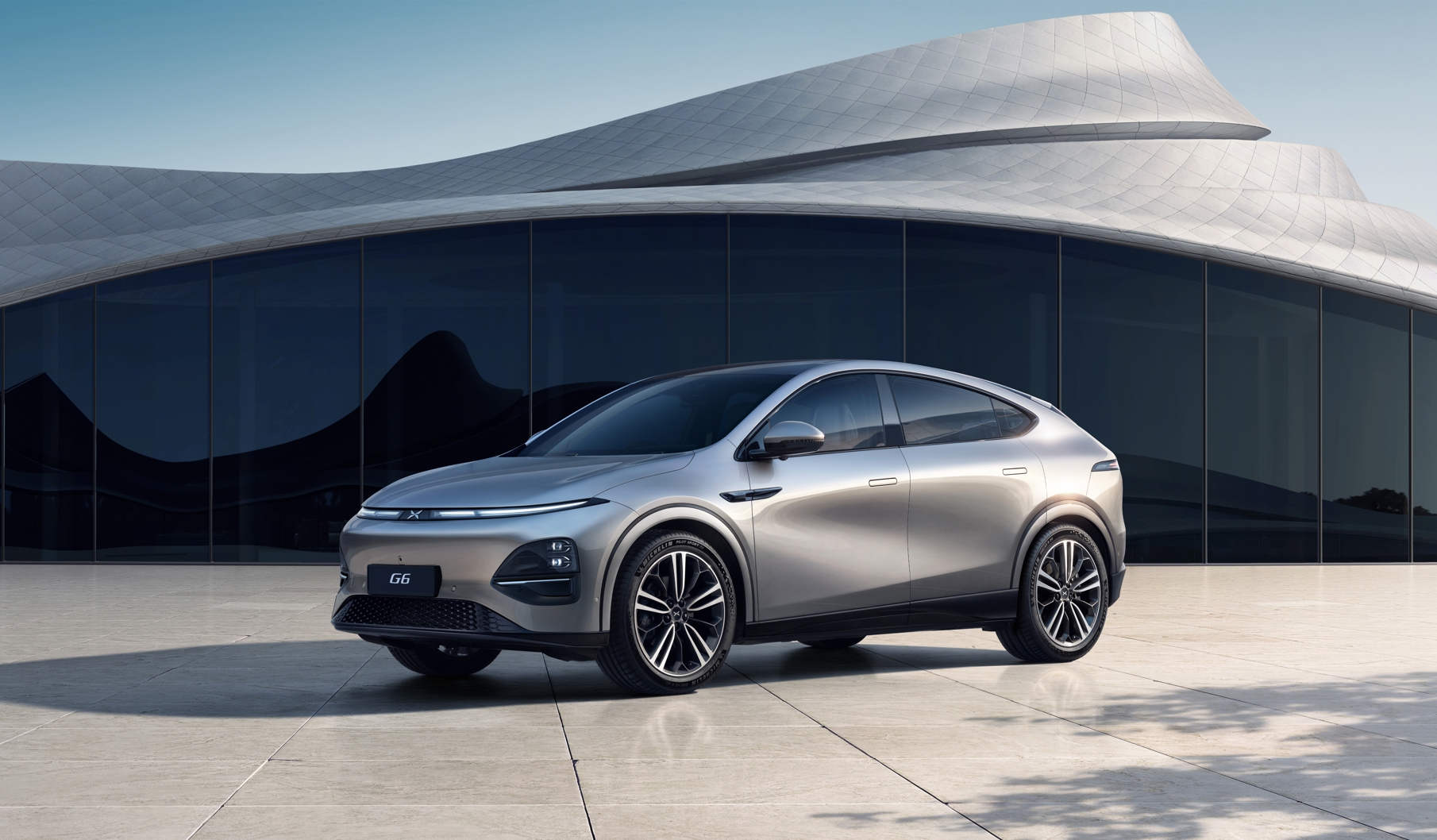 XPeng G6, un SUV coupé électrique, garé sur une station de recharge futuriste, mettant en valeur sa silhouette élégante et sa technologie avancée.