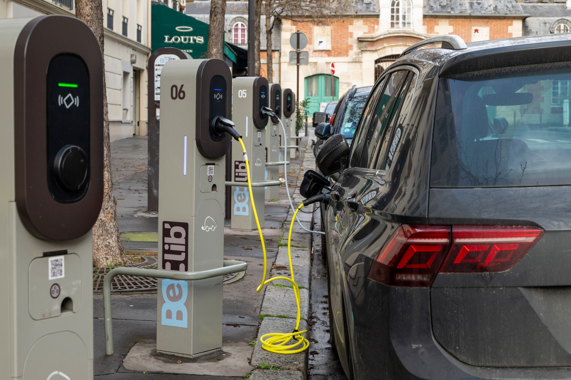 Borne de recharge pour véhicules électriques devant un bâtiment historique à Versailles.