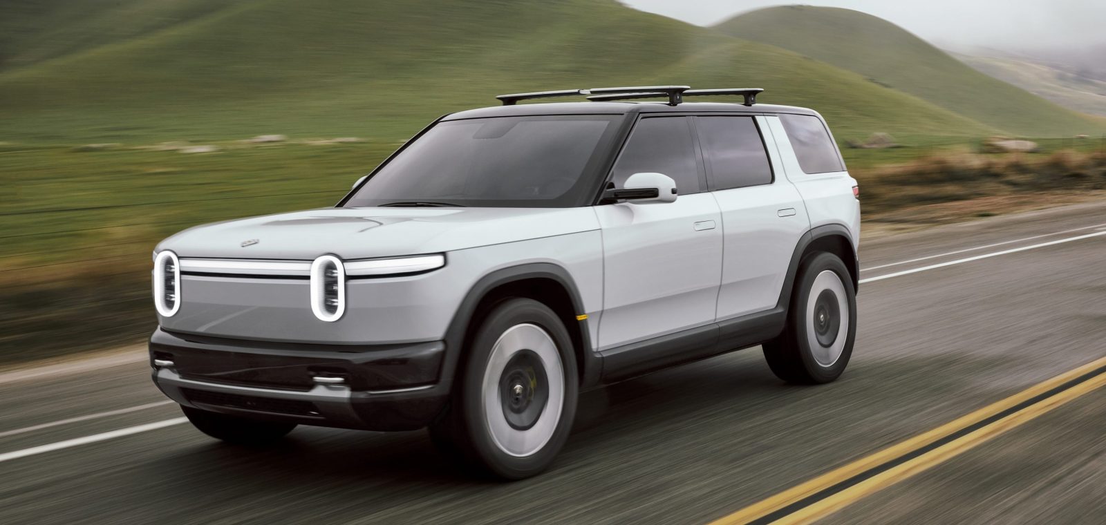 Vue extérieure du Rivian R2, mettant en évidence ses phares verticaux et sa bande lumineuse horizontale.