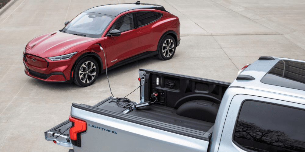 Un Ford F-150 Lightning et un Ford Mustang Mach-E en charge à une station de recharge électrique.