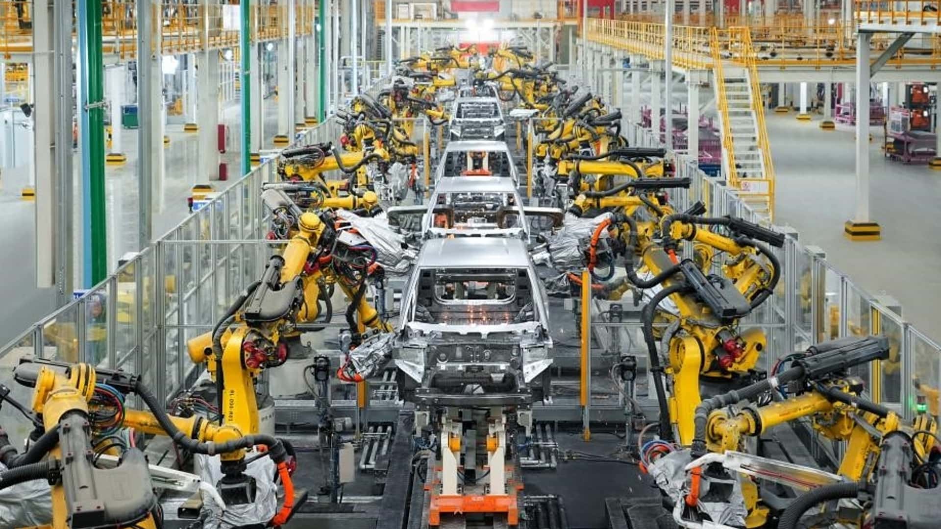Vue d'ensemble d'une usine de fabrication de voitures électriques en Europe, avec des robots assemblant des véhicules.