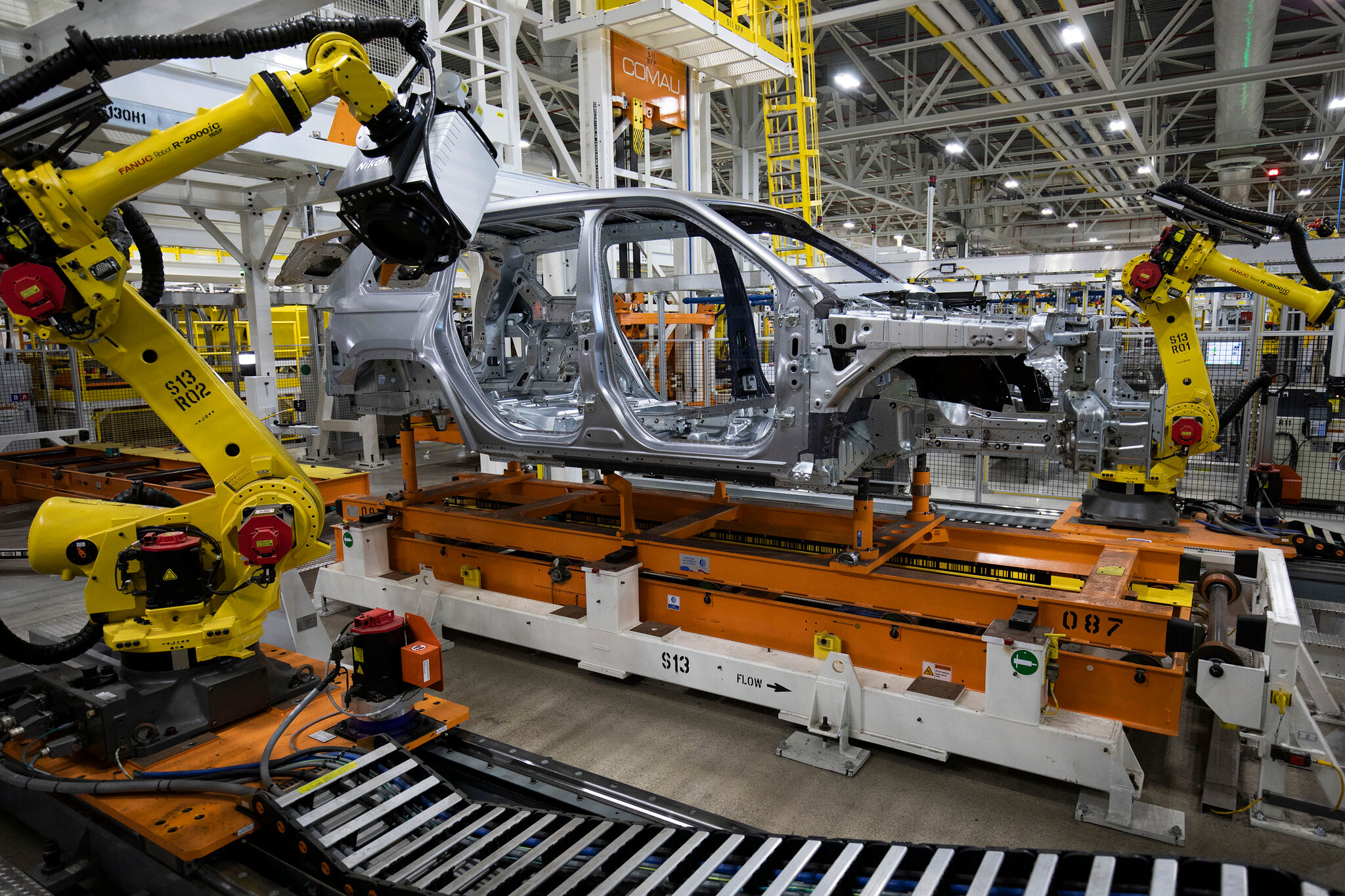 Des bras robotiques assemblent des batteries de véhicules électriques sur une ligne de production moderne et automatisée dans une usine Stellantis.