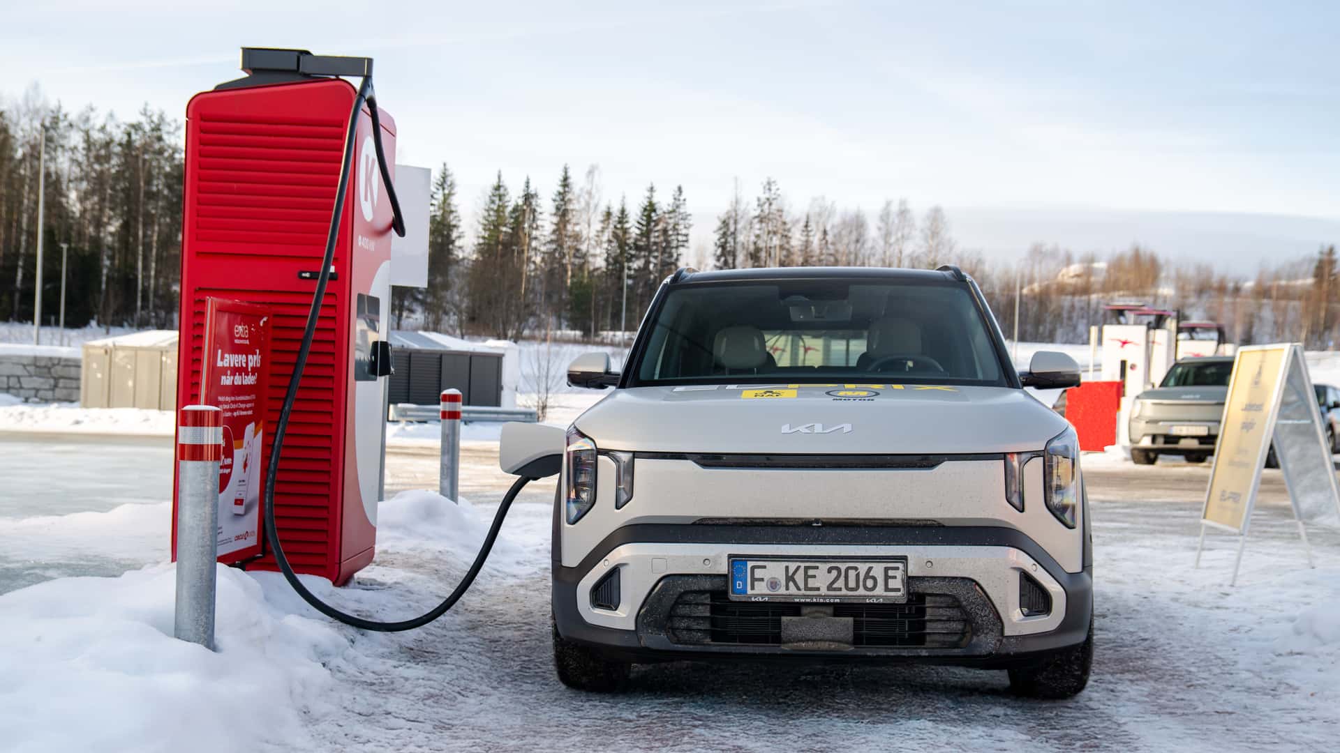 Un Kia EV2 branché à une borne de recharge rapide dans un environnement enneigé et froid.