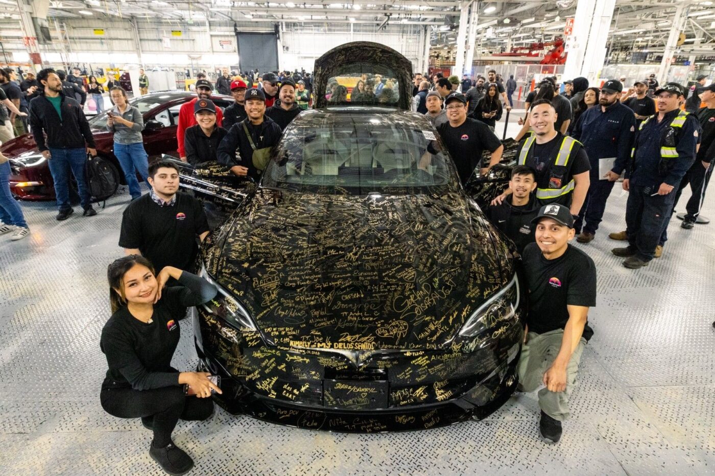 Une Tesla Model S noire couverte de signatures d'ouvriers, symbolisant la fin de sa production à l'usine de Fremont.