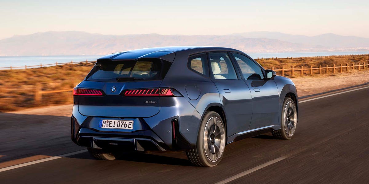 Vue latérale d'une BMW iX3 50 xDrive 2026 blanche, roulant sur une autoroute au coucher du soleil, mettant en valeur son design moderne et ses jantes de 21 pouces.