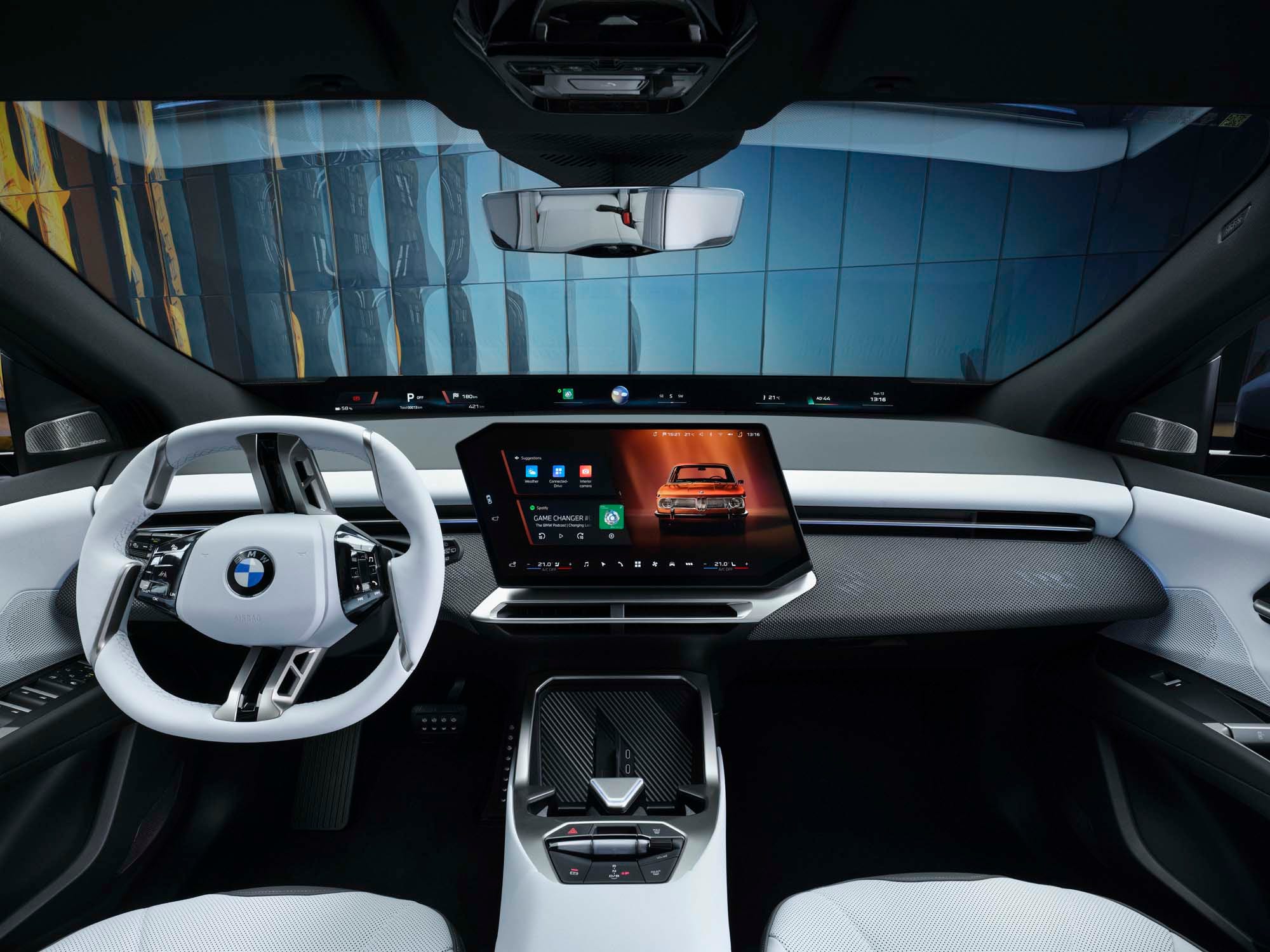 Tableau de bord de la BMW iX3 50 xDrive 2026, montrant l'écran incurvé, le volant et les sièges en cuir noir.
