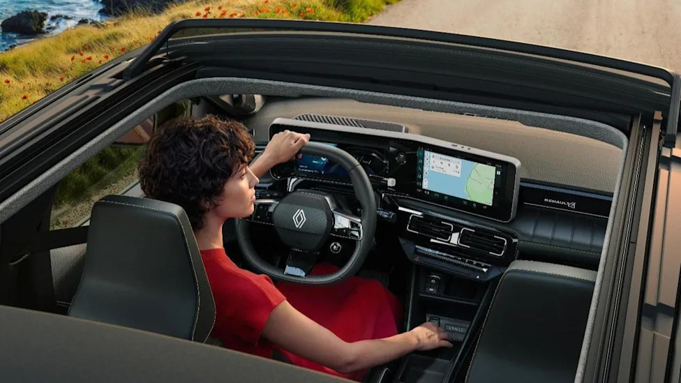 L'intérieur d'une Renault R4 E-Tech Plein Sud, montrant le tableau de bord moderne, l'écran tactile et le toit ouvert.