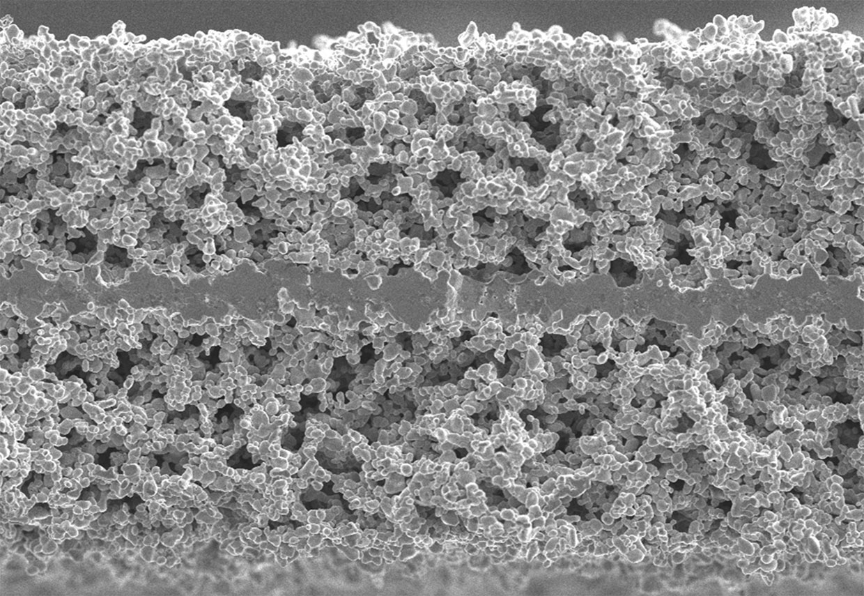 Vue en coupe d'une batterie à électrolyte solide, montrant les différentes couches et l'électrolyte en céramique.