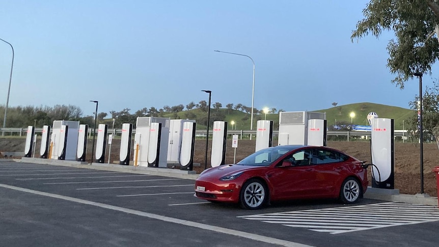 Plusieurs voitures électriques faisant la queue à une station de recharge publique bondée en ville.