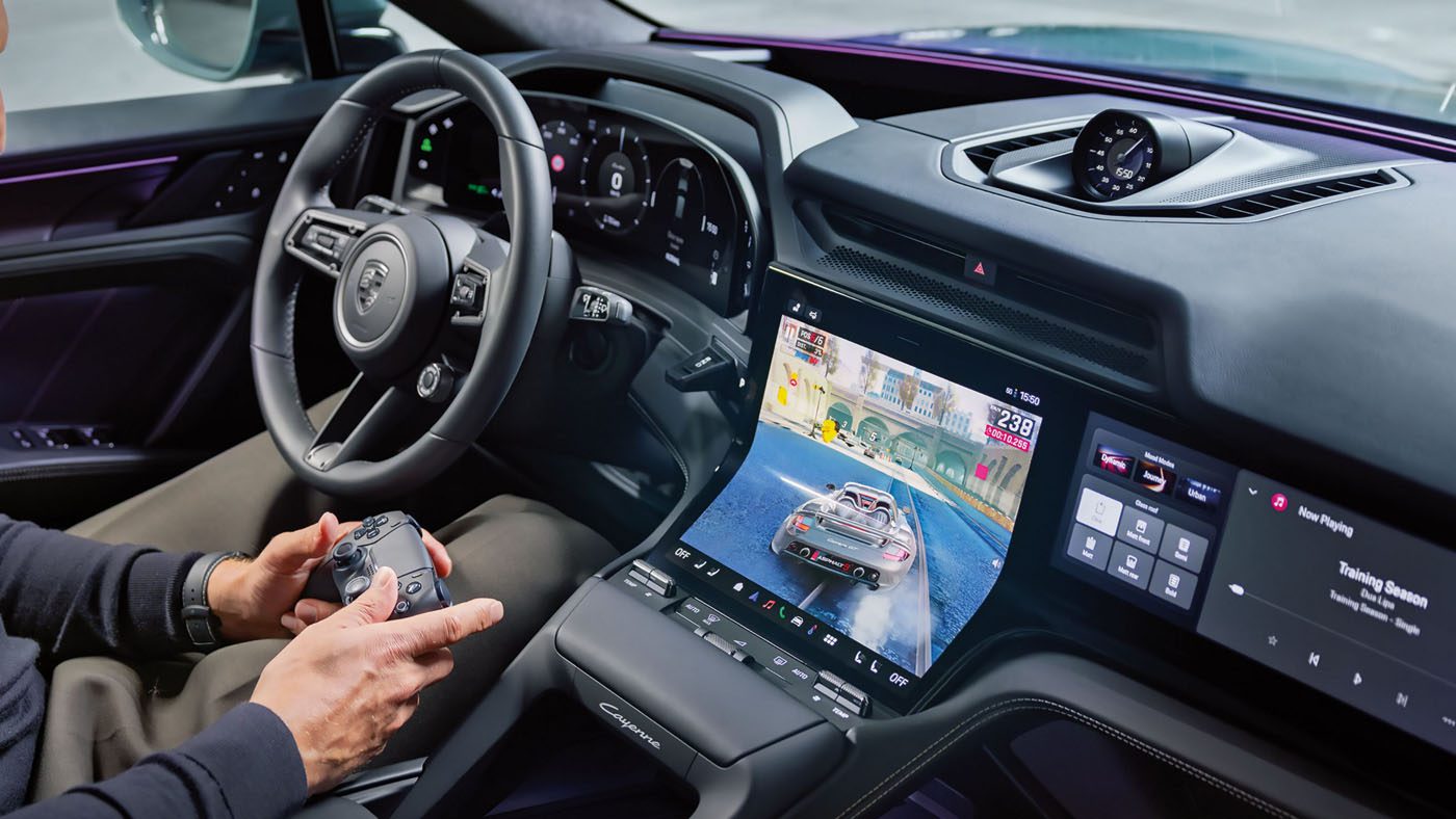 Vue de l'intérieur d'une voiture électrique, montrant le tableau de bord numérique et le volant. La route est visible à travers le pare-brise, suggérant une conduite fluide.