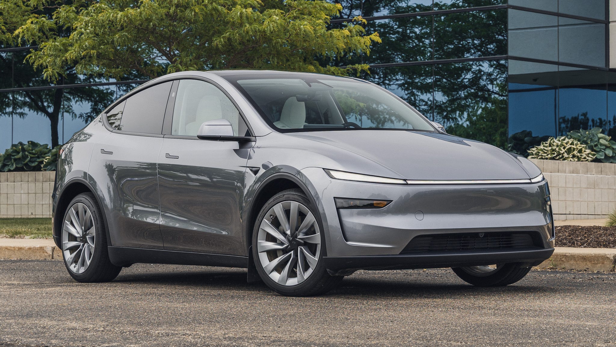 Un Tesla Model Y blanc garé dans une rue de ville moderne, avec des bâtiments en arrière-plan.
