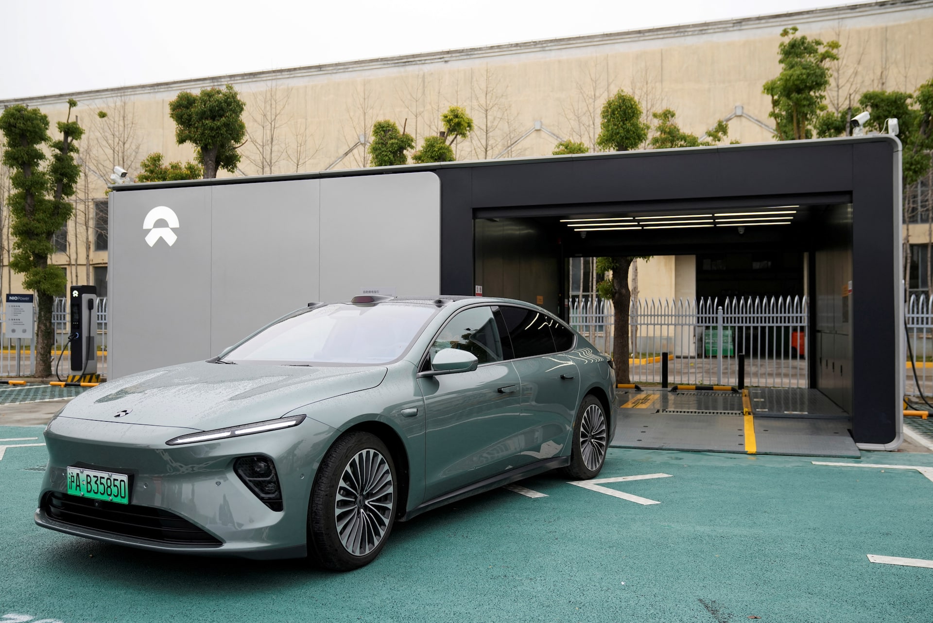 Une rue animée dans une ville chinoise moderne avec plusieurs voitures électriques de marques chinoises comme BYD et Nio. Des bâtiments modernes et des panneaux d'affichage sont visibles en arrière-plan.