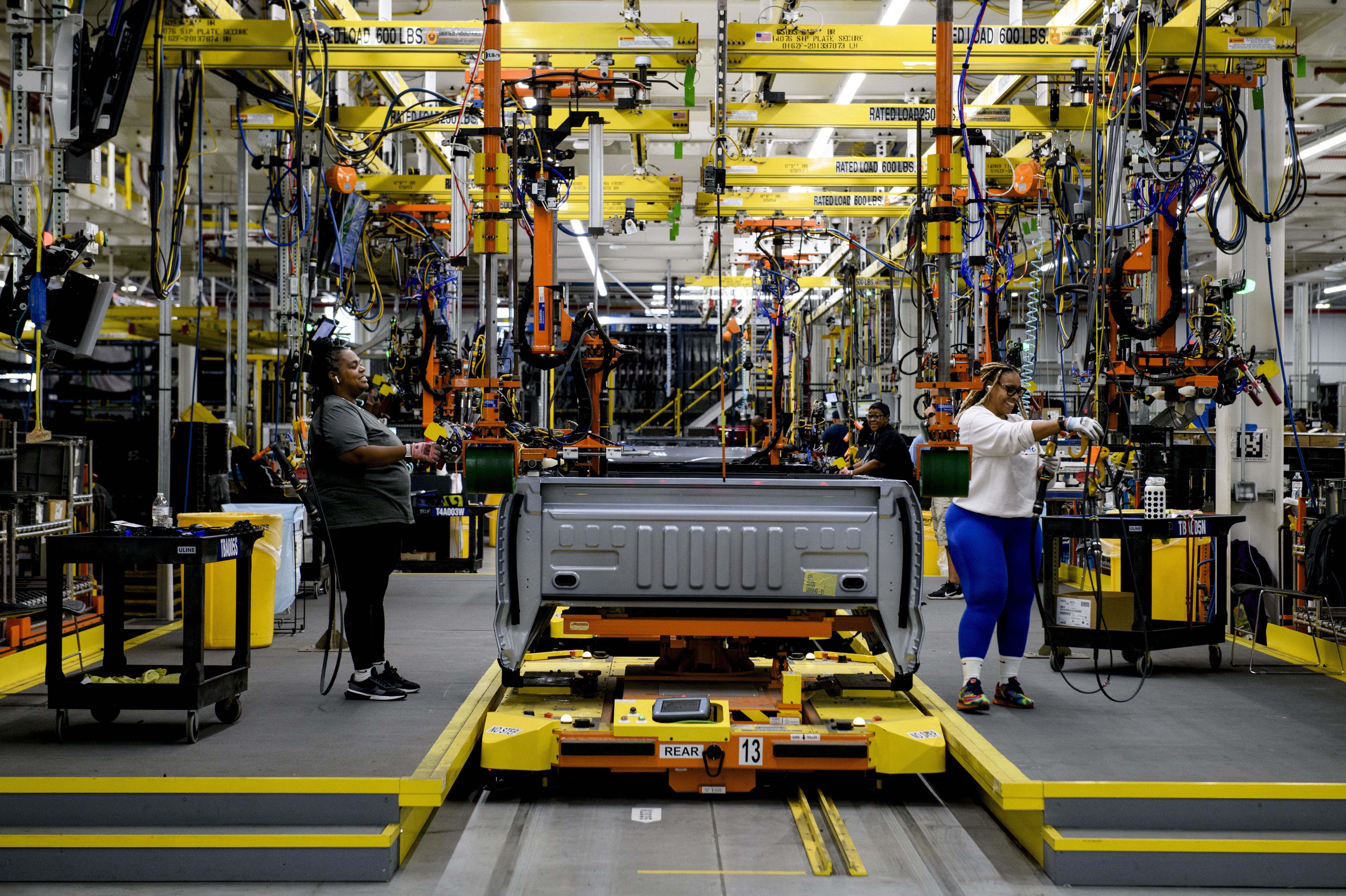 Vue d'une chaîne de montage de véhicules électriques avec des robots et des ouvriers.