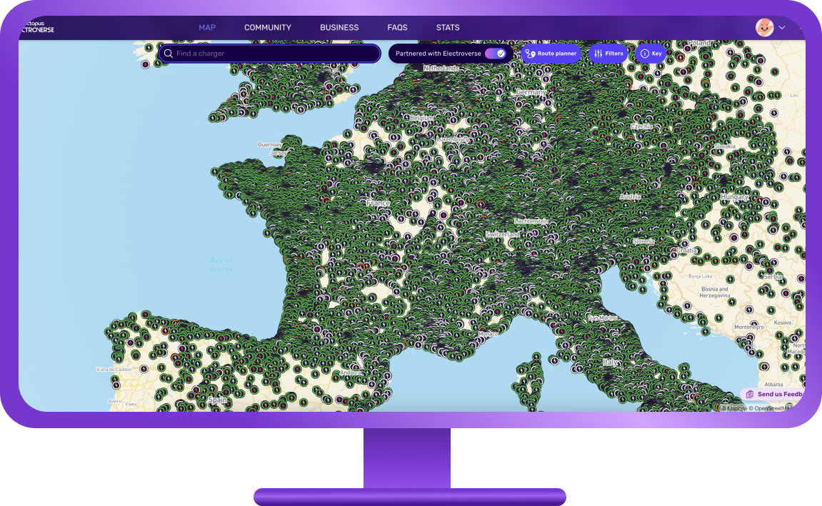 Une borne de recharge électrique moderne située dans un paysage rural français verdoyant, avec un petit village en arrière-plan.