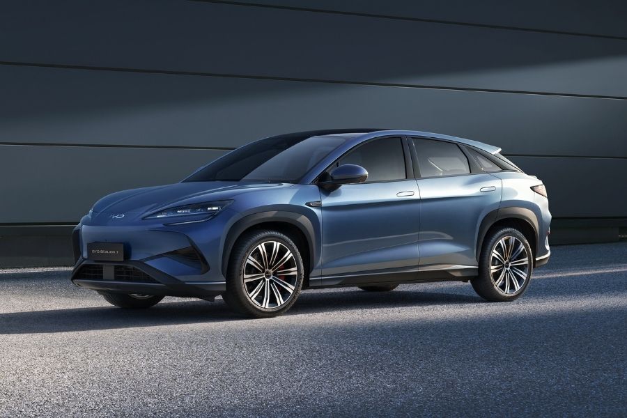 Une voiture électrique BYD Sealion 7 blanche roulant sur une route côtière australienne ensoleillée.