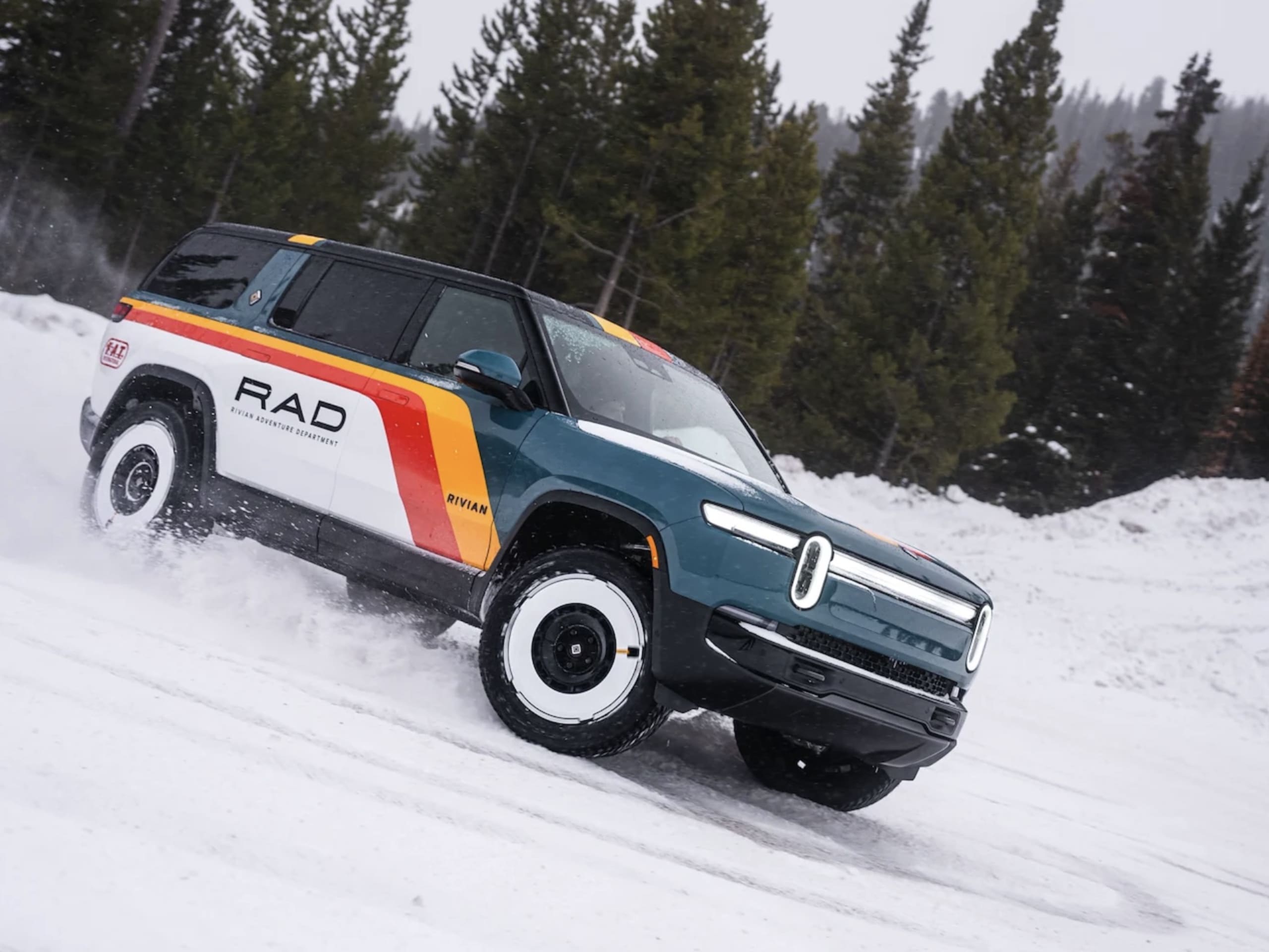 Un Rivian R1T ou R1S RAD en action sur un terrain accidenté, soulevant de la poussière, avec un ciel dramatique en arrière-plan.