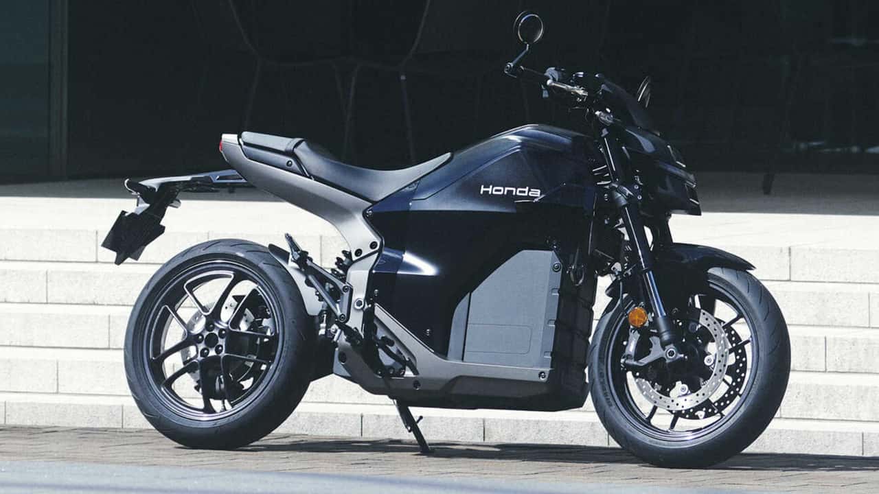 Une Honda WN7 électrique garée dans un environnement urbain, mettant en valeur son design roadster futuriste et ses lignes épurées.