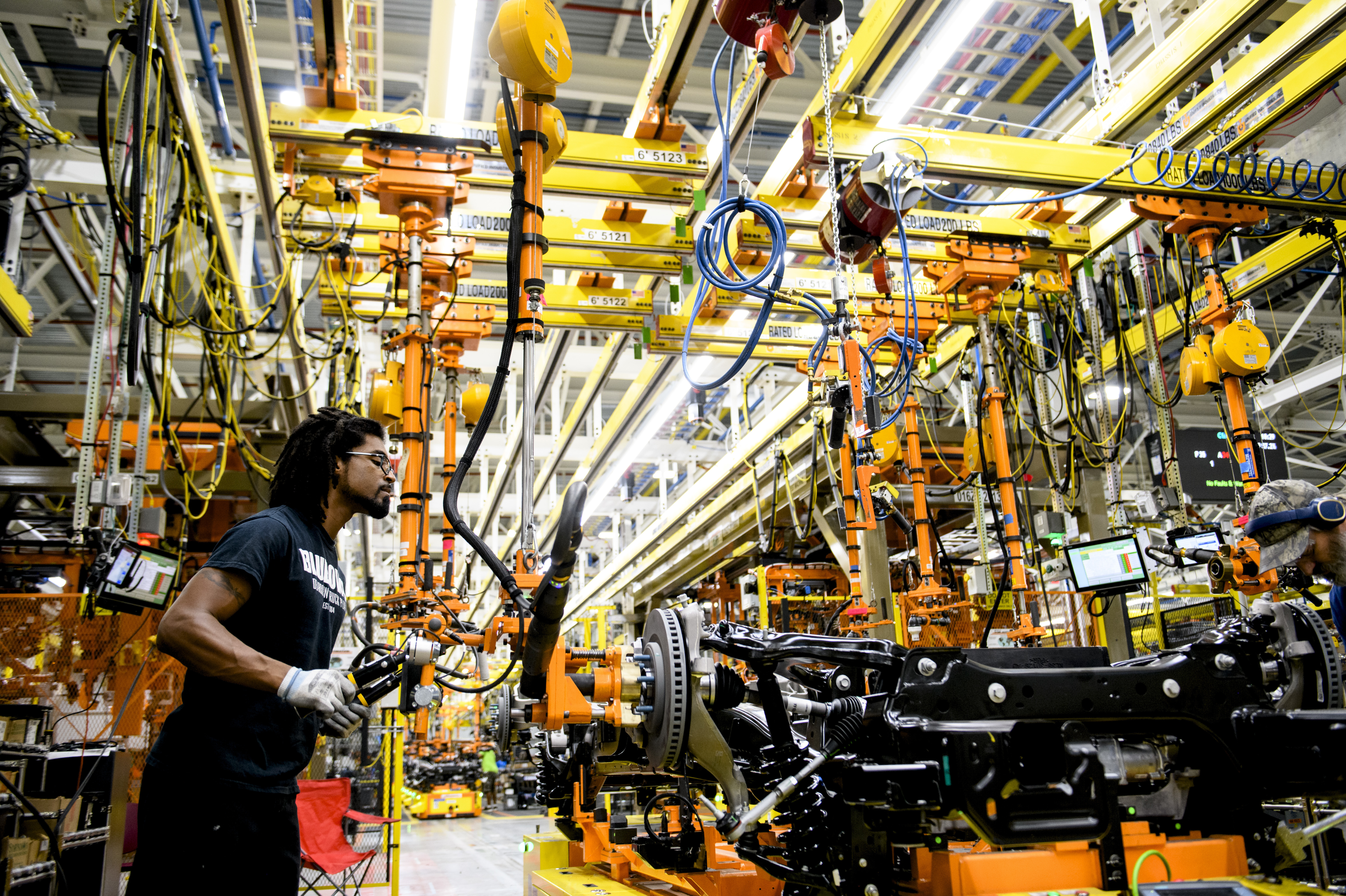 Vue d'une chaîne de montage moderne dans une usine de voitures électriques, montrant des robots et des ouvriers assemblant des véhicules.