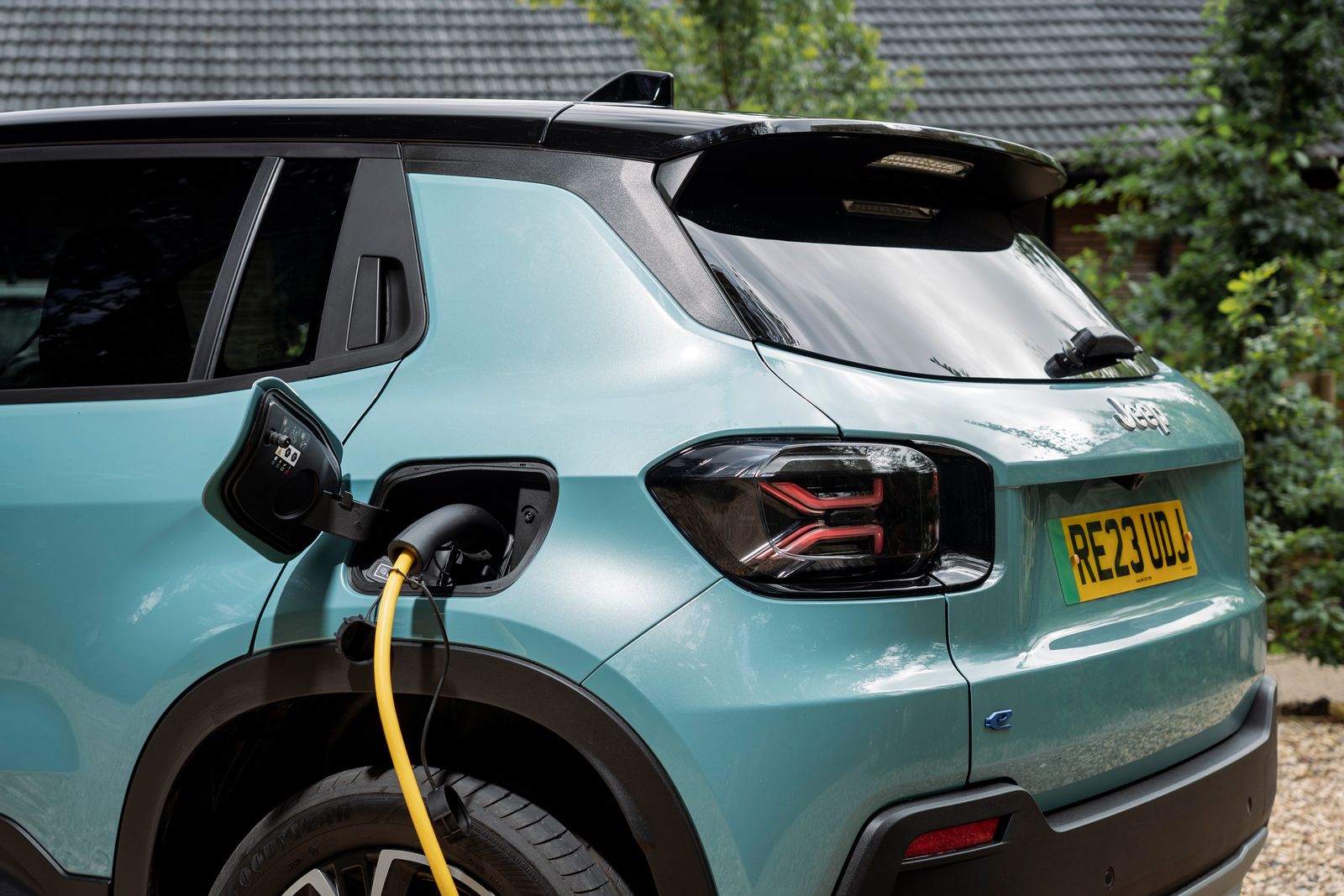 Une Jeep Avenger électrique blanche branchée à une borne de recharge dans un environnement urbain.