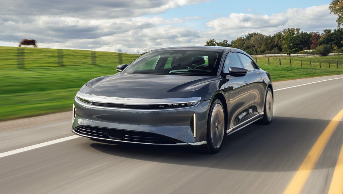 Une Lucid Air Grand Touring argentée de 2026 roulant sur une autoroute panoramique au coucher du soleil.