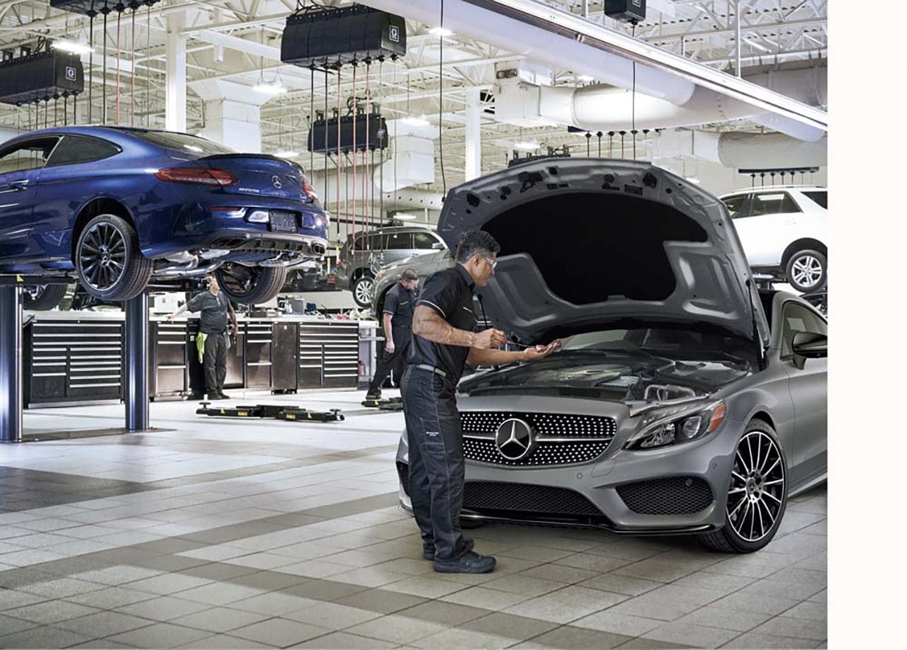 Mécaniciens inspectant une Mercedes-Benz dans un garage, représentant les interventions techniques après un rappel.