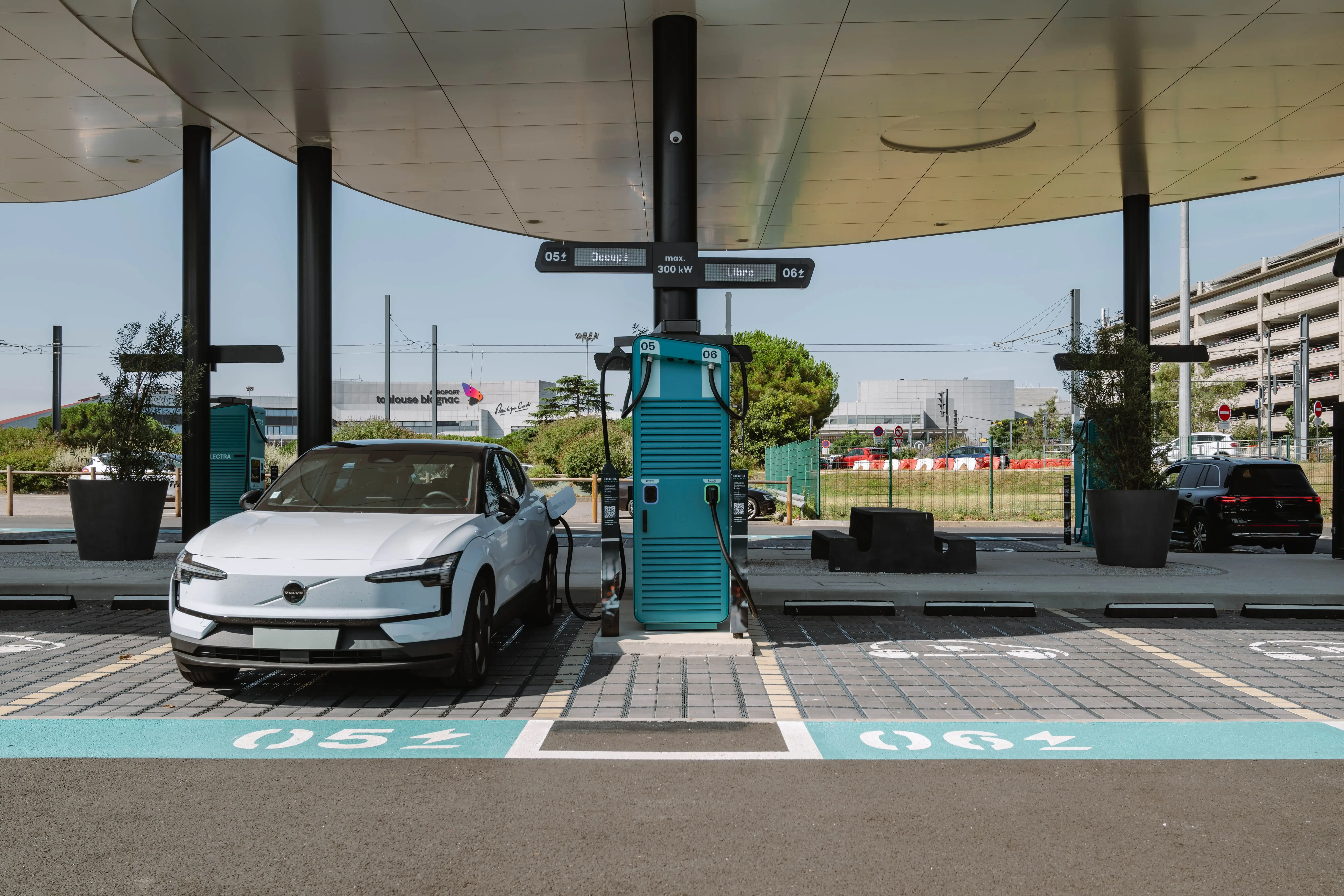 Une voiture électrique moderne et élégante roule dans une rue de ville propre avec des panneaux ZFE visibles, représentant l'avenir de la mobilité urbaine.