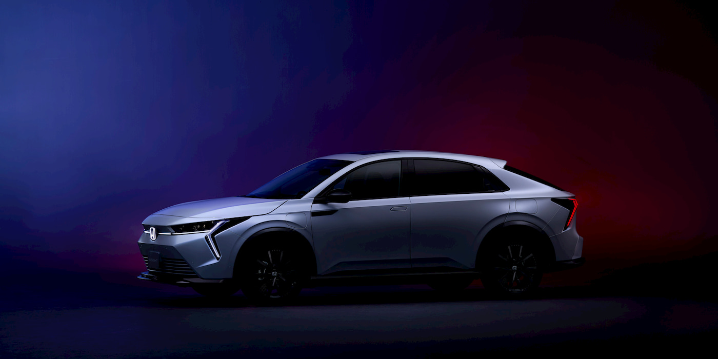 Vue extérieure de la Honda Insight électrique 2026, un crossover compact au design futuriste, garé en ville au coucher du soleil.