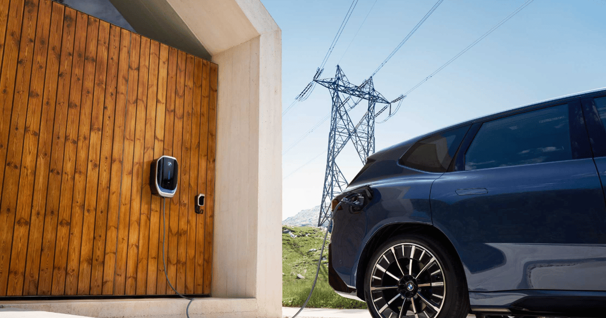 Une vue aérienne de centaines de voitures électriques garées en Allemagne, toutes connectées à des bornes de recharge V2G, illustrant l'expérimentation à grande échelle.