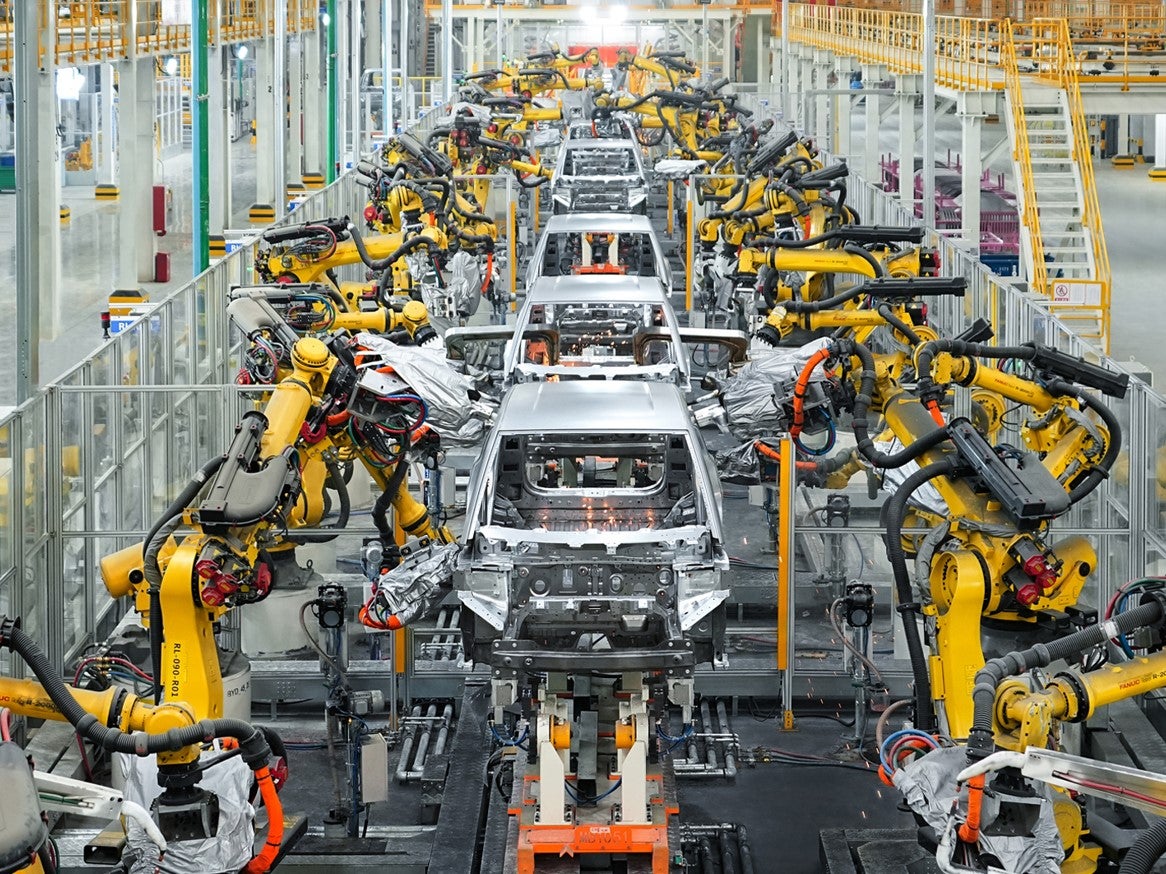 Vue intérieure d'une usine de fabrication de voitures BYD en Hongrie, montrant des robots assemblant des véhicules électriques.
