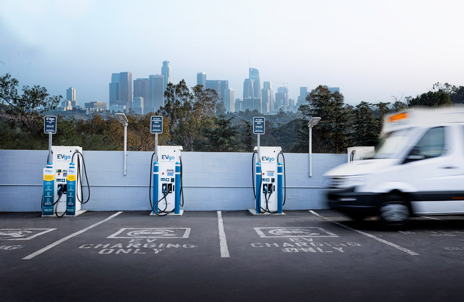 Plusieurs véhicules électriques de différentes marques et modèles sont branchés à des bornes de recharge dans un environnement urbain ou industriel.
