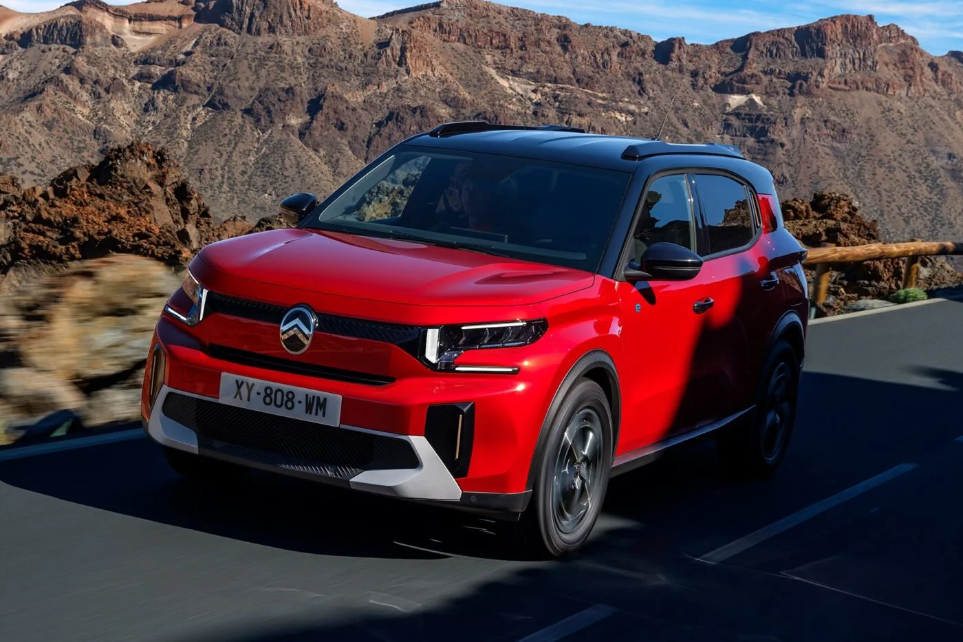 Flotte de Citroën ë-C3 Aircross électriques blanches garées devant un immeuble de bureaux moderne avec une borne de recharge.