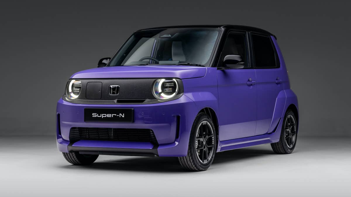 Une Honda Super-N électrique, compacte et au style rétro-sportif, garée dans une rue urbaine animée.