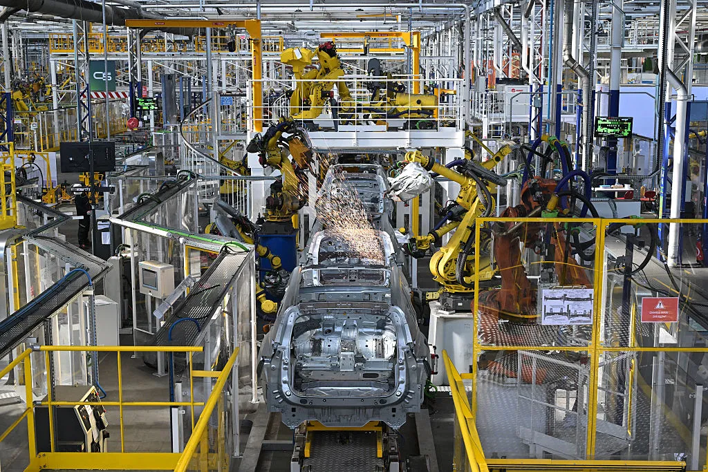 Une chaîne de montage automobile moderne avec des robots et des humains assemblant des voitures, symbolisant la collaboration industrielle.